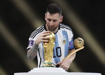 2022年12月18日，获得世界杯金球奖的梅西在颁奖仪式上注视大力神杯。