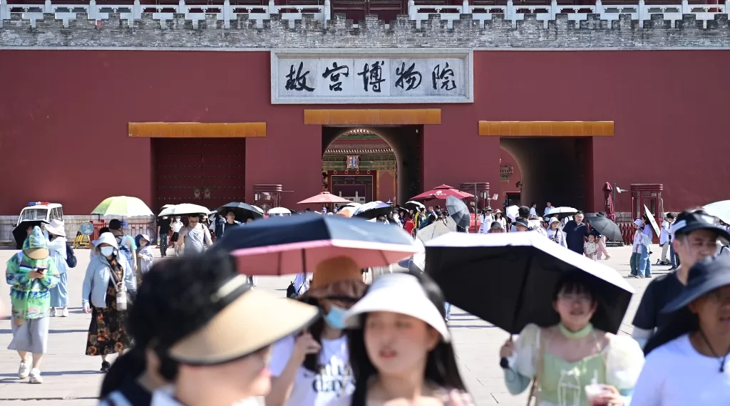 6月22日,北京故宫博物院游客撑伞、戴遮阳帽防晒。