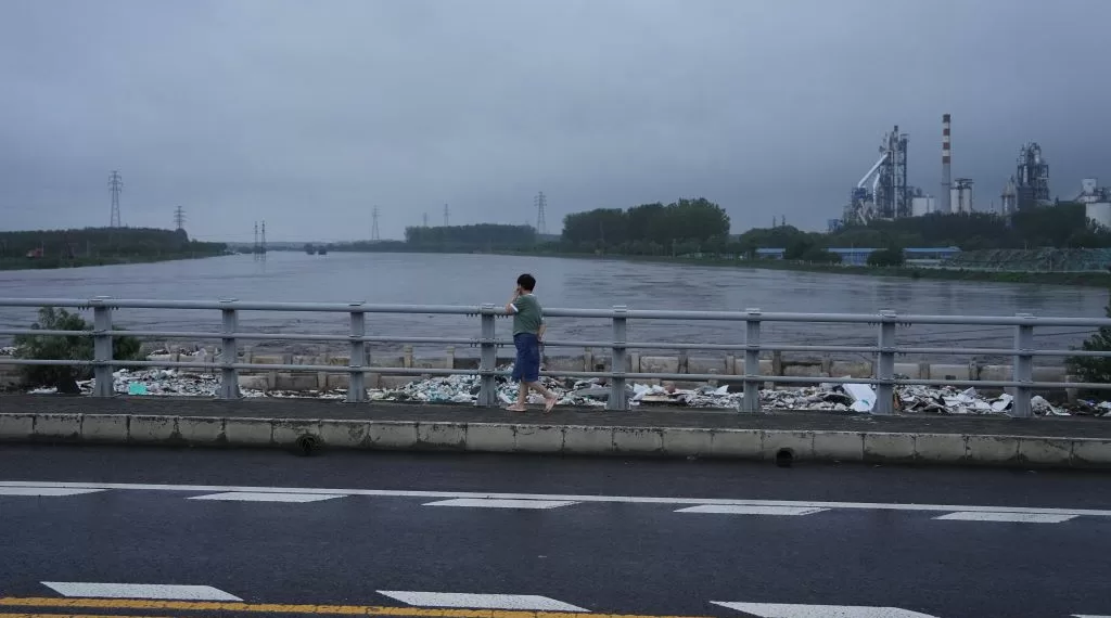 7月31日,北京市房山区,市民步行经过横跨大石河的琉璃河桥。当日上午,房山区大石河流域出现超标准洪水,沿线多处出现险情。31日10时,北京市气象台发布分区域暴雨红色预警信号。北京市水文总站发布洪水红色预警。